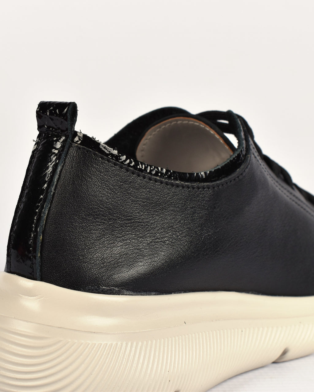 Deck Sneaker in Black, close-up of the heel tab and crinkle-patent trim