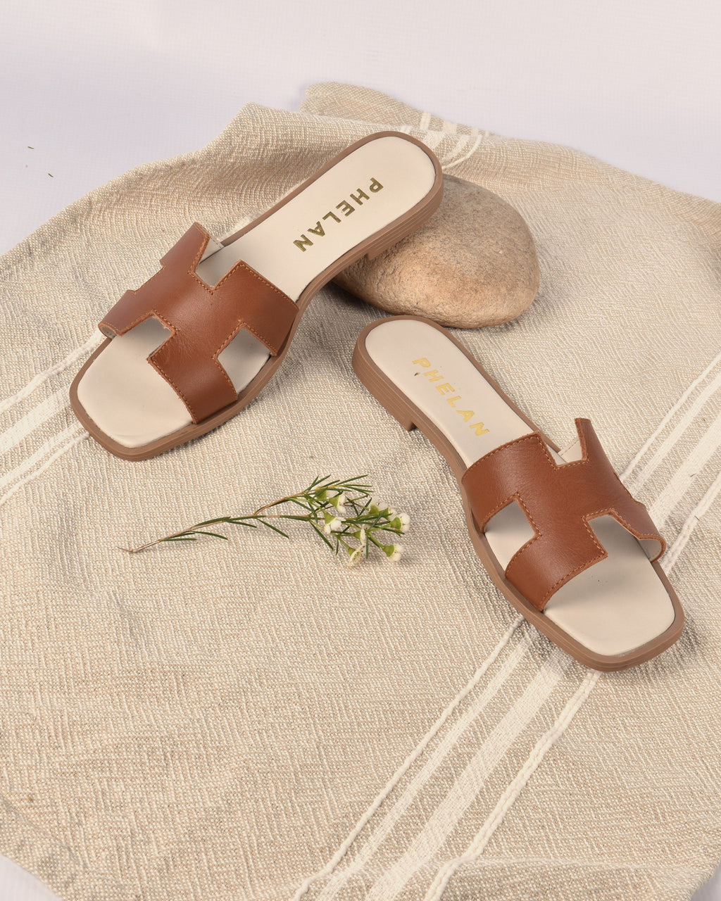 Santorini Slide in Tan on a linen throw with a stone and fynbos