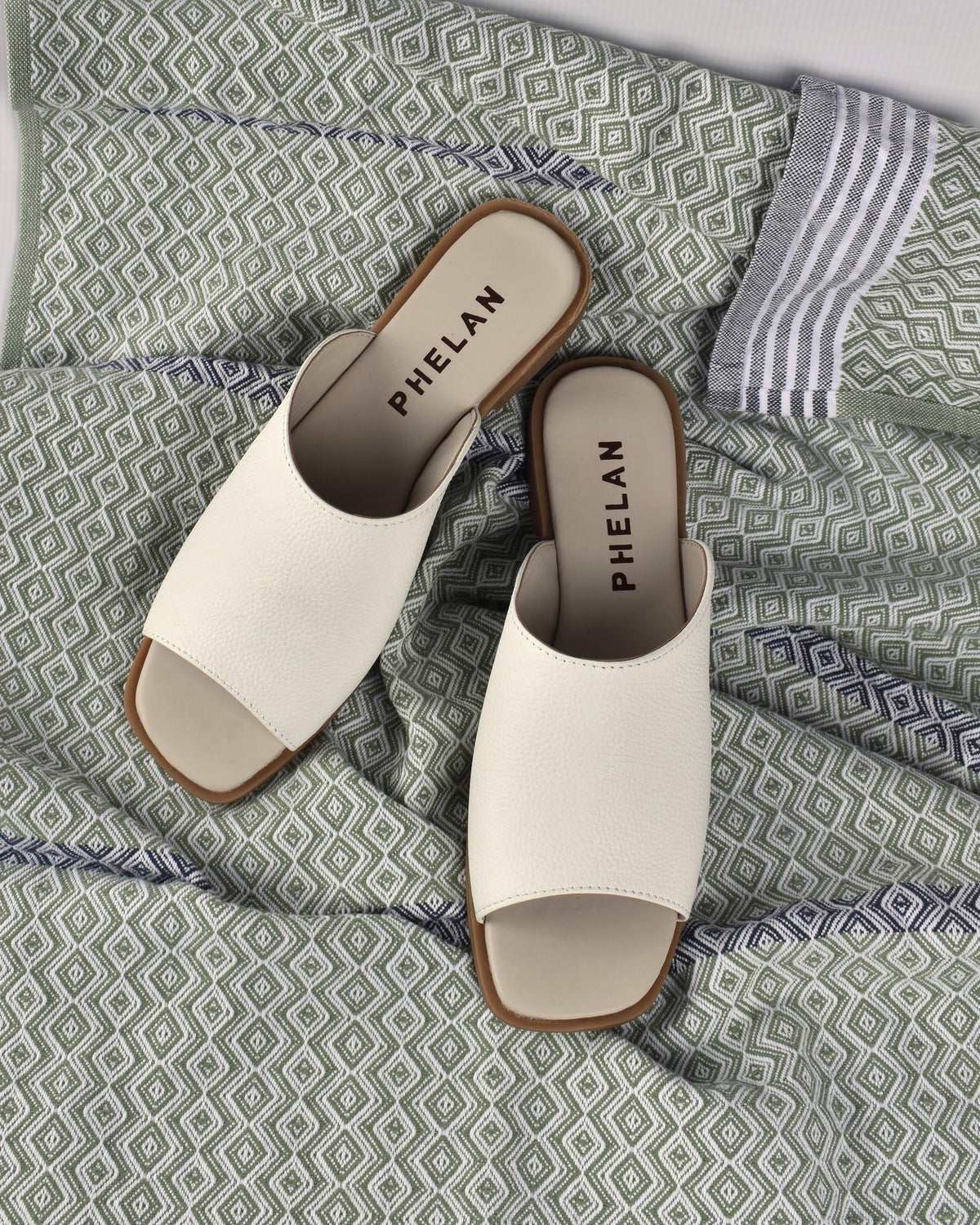 Mykonos Slide in White on a sage patterned throw
