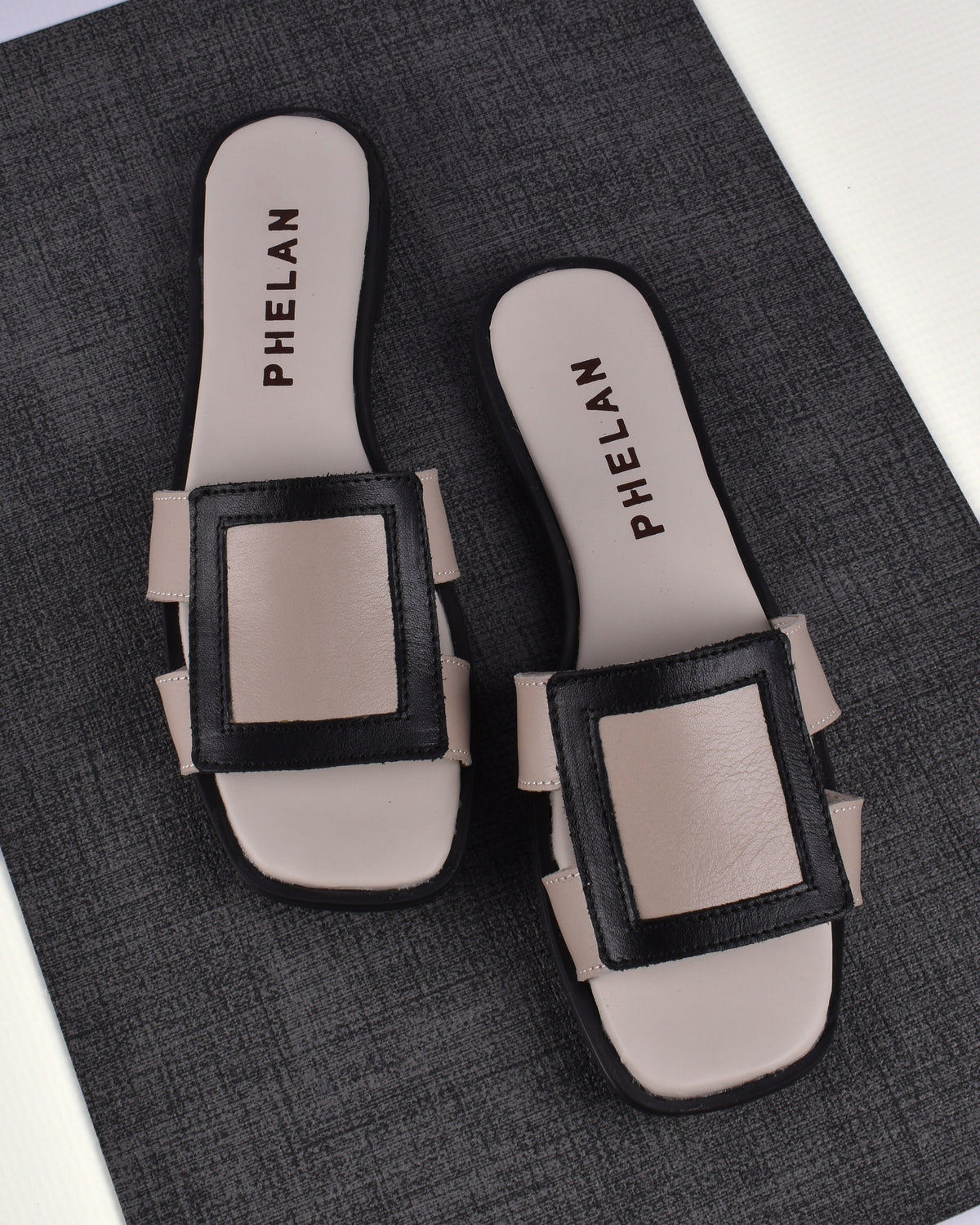 Coco Slide in Mink/Black leather on a charcoal linen mat