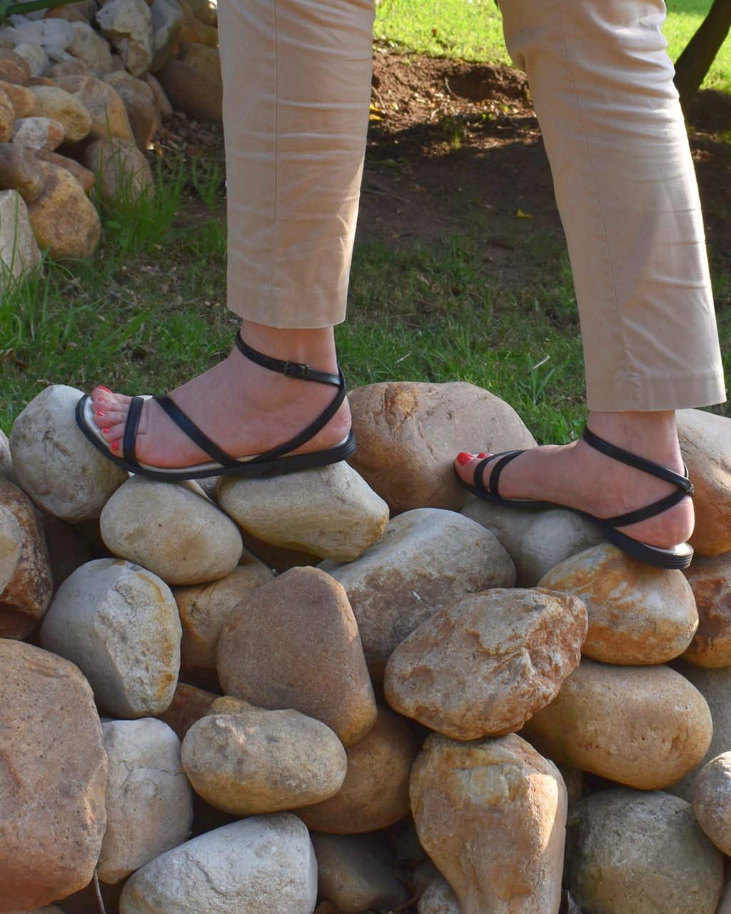 Mila Sandal in Black, worn, on river stones