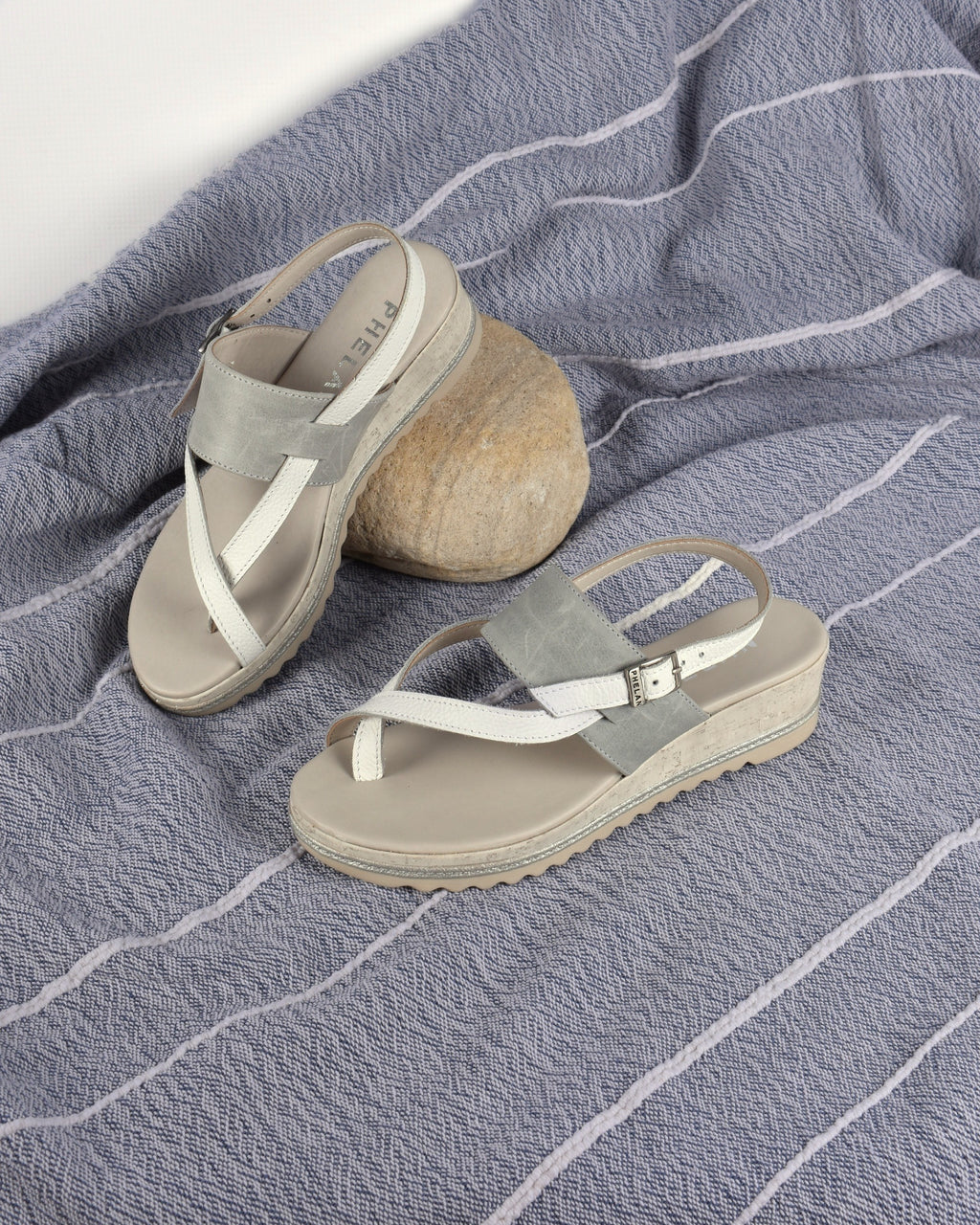 Anchor Wedge in White/Grey on a blue-grey throw with a pebble
