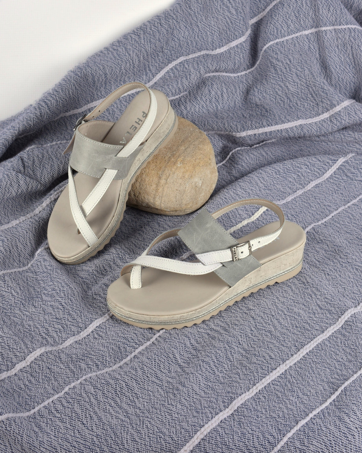 Anchor Wedge in White/Grey on a blue-grey throw with a pebble