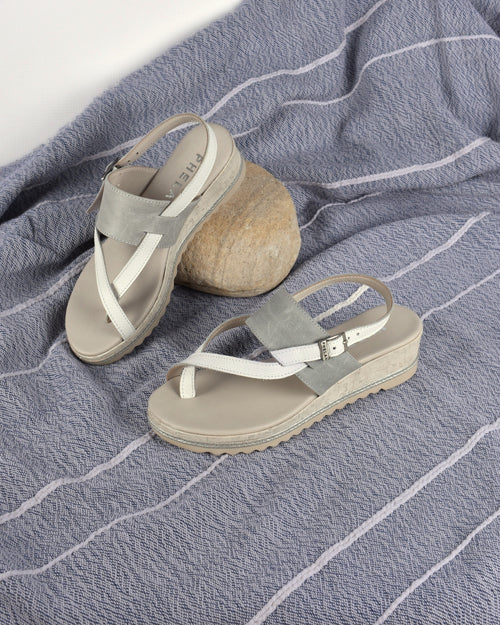 Anchor Wedge in White/Grey on a blue-grey throw with a pebble