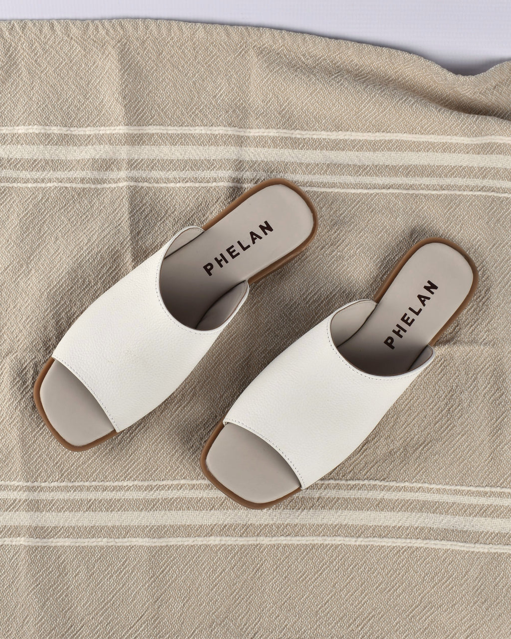 Mykonos Slide in White on a striped linen throw