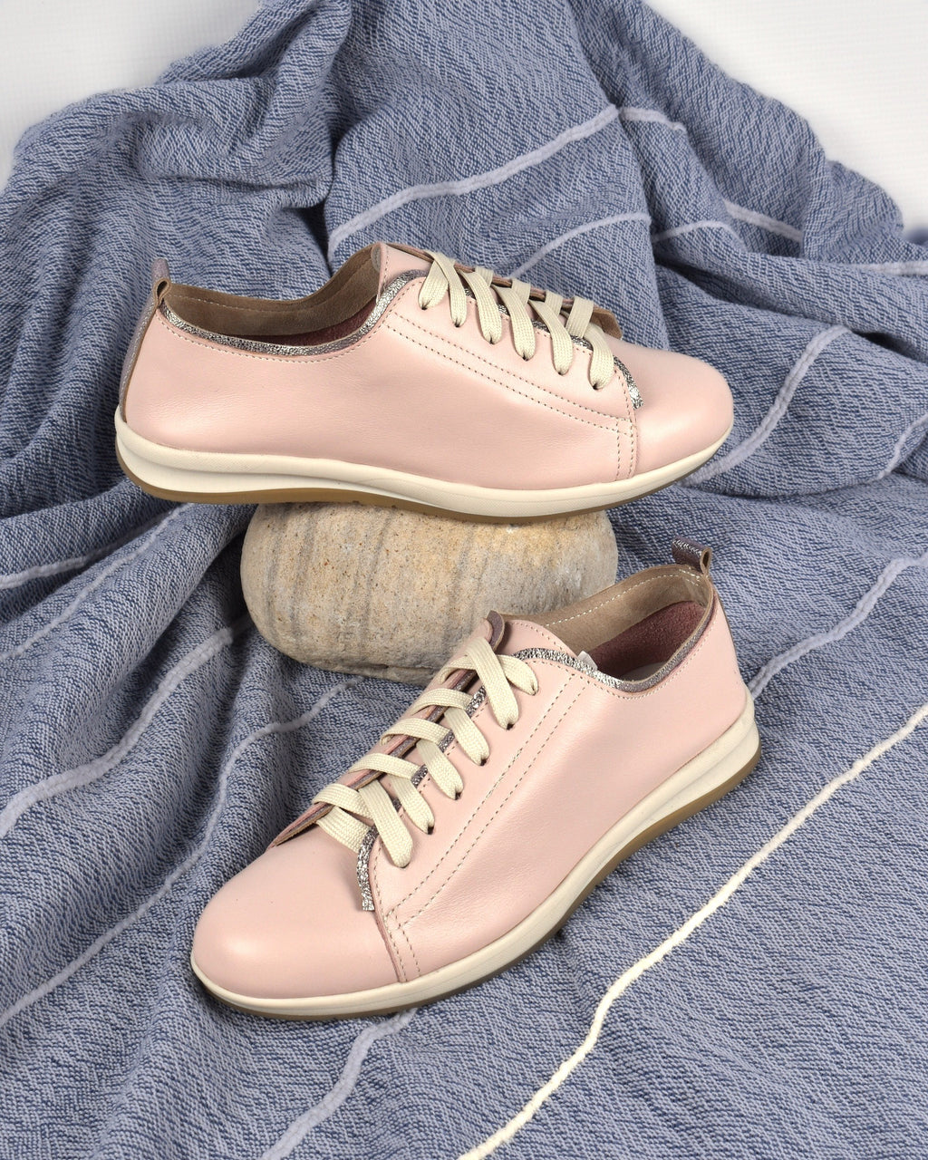 Hydra Sneaker in Blush/Silver on a blue-grey throw with a sandstone pebble