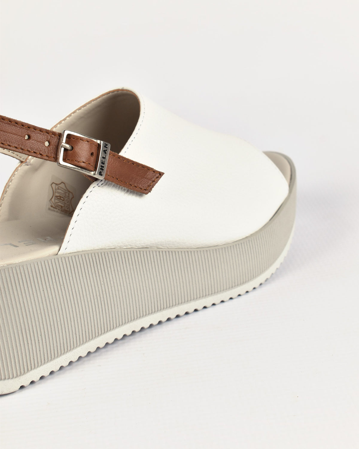 Corsica Platform in White/Tan, close-up of the tan strap and PHELAN buckle
