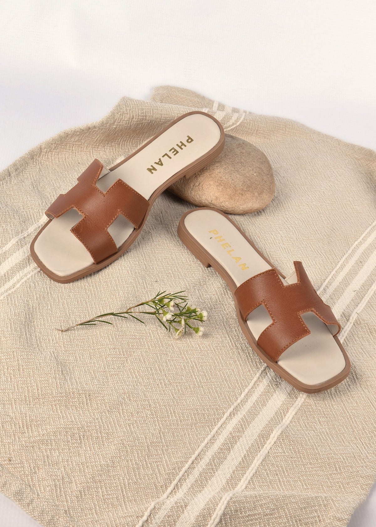 Santorini Slide in Tan on a hand-woven Barrydale cloth with a stone and a sprig of fynbos