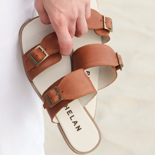 Buckle Sandal in Tan held in the hand, showing the double PHELAN buckles